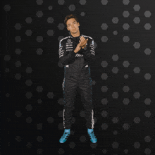 a man in a mercedes suit is clapping his hands in front of a black background
