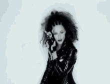 a woman with curly hair is holding a microphone in her hand and dancing .