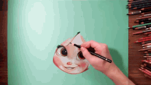 a person is drawing a face with a pencil on a piece of paper