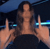 a woman in a black dress is giving the middle finger to the camera .
