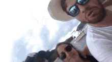 a man and a woman wearing sunglasses and a hat are taking a picture of themselves .