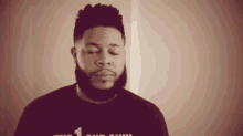 a man with a beard is standing with his eyes closed in a room .