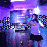 a woman singing into a microphone in front of a screen that says ass ass ass ass