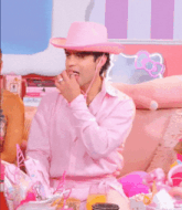 a man wearing a pink cowboy hat is sitting on a couch