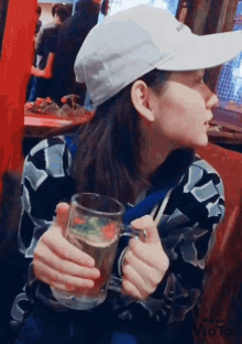 a woman wearing a white hat holds a glass of water