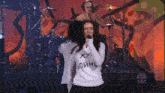 a woman sings into a microphone while wearing a shirt that says ' xxi ' on it