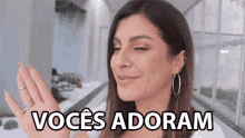 a woman wearing hoop earrings and a nose ring says vocês adoram in a foreign language .