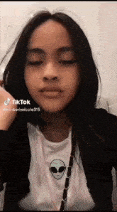 a girl wearing a black jacket and a white shirt with an alien on it .