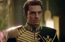 a man in a green and gold military uniform looks at the camera with a serious look on his face