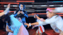 a group of people are dancing on a stage with a man taking a picture .