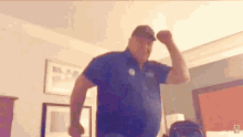 a man in a blue shirt flexes his muscles in a room