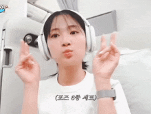 a woman wearing headphones giving a peace sign