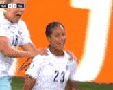 a soccer player with the number 23 on her jersey is being congratulated by another player