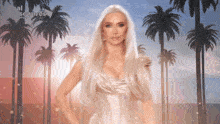 a woman in a white dress is standing in front of palm trees and a sign that says real wives