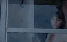 a woman is looking out of a window .