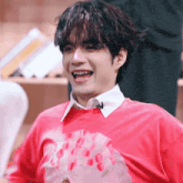 a young man wearing a red shirt with a strawberry on it is smiling