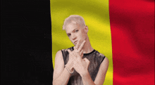 a man in front of a belgian flag giving the peace sign