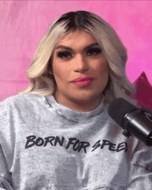 a woman wearing a born for speed sweatshirt is standing in front of a microphone