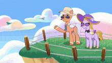 a couple of ponies standing next to each other on top of a grassy hill