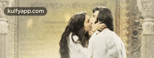 a man and a woman are kissing in front of a temple .