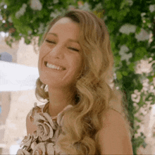 a woman in a dress with flowers on it smiles with her eyes closed
