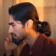 a man with long hair and a ponytail is talking on a phone
