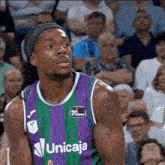 a basketball player in a purple and green uniform with the word unicaja on it