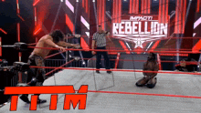two men in a wrestling ring with a sign that says rebellion in the background
