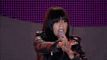 a woman singing into a microphone with a bottle of aquafina water