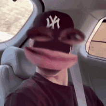 a man wearing a ny hat and glasses is sitting in a car with a mask on his face .