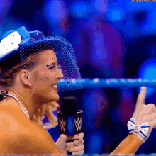 a woman wearing a blue hat is holding a microphone with the letter w on it