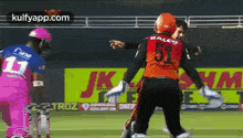 a cricket player wearing a number 51 jersey is hugging another player .