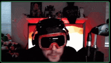 a man wearing goggles and headphones is sitting in front of a computer screen