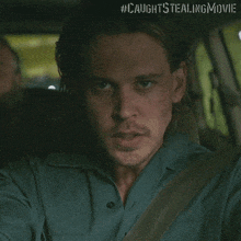 a close up of a man in a car with the hashtag #caughtstealingmovie on the bottom