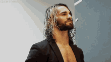 a man with long hair and a beard wearing a black jacket
