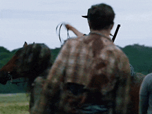 a man riding on the back of a horse holding a rifle