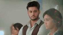 a man with a beard and a vest stands next to a woman