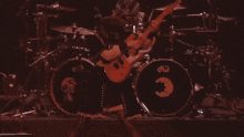 a woman is playing a pink electric guitar on stage .
