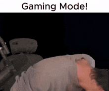 a man is laying down in a chair with his head down and the words `` gaming mode '' written above him .