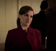 a woman in a red jacket makes a funny face