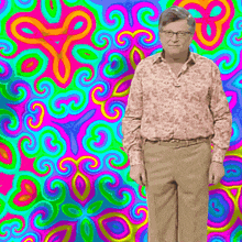 a man with glasses stands in front of a psychedelic background