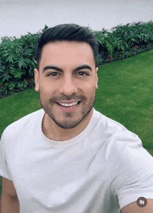 a man in a white shirt is smiling and taking a picture