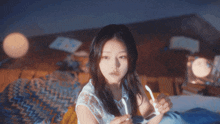 a young girl laying on a bed holding a lighter