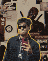 a man taking a selfie in front of a wall with deadpool posters on it