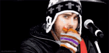 a man wearing a hat with a skull on it is singing into a microphone while holding an umbrella .