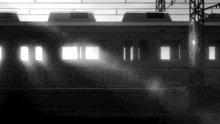 a black and white photo of a subway train going down the tracks .