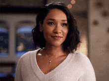 a woman is wearing a white sweater and a necklace and smiling .