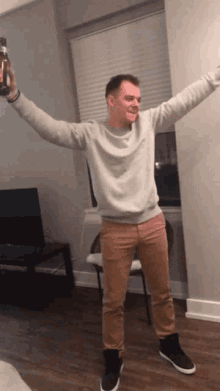 a man in a grey sweater is holding a bottle in his hands