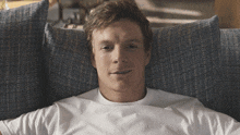 a man in a white shirt is laying on a blue couch and smiling