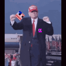 a man in a suit and tie is holding an american flag and wearing a red maga hat